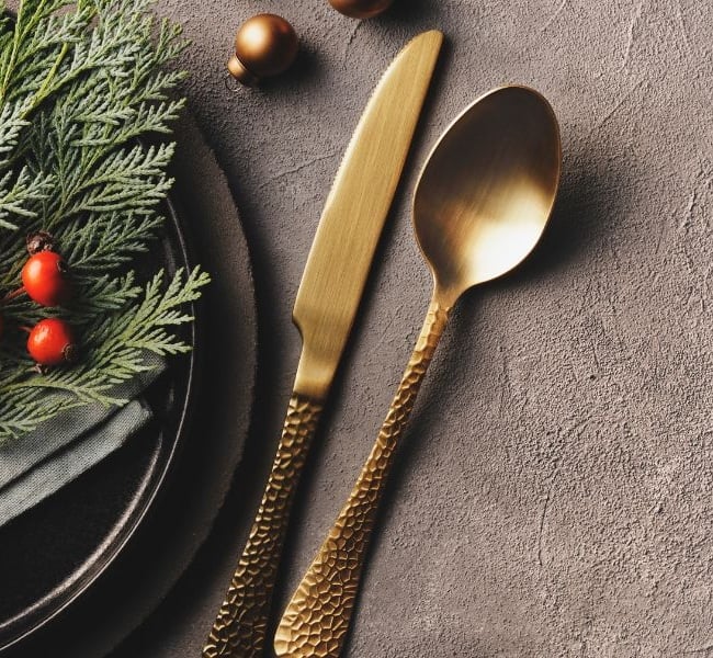 Festive Holiday Plate with evergreens, berries, and brass utensils