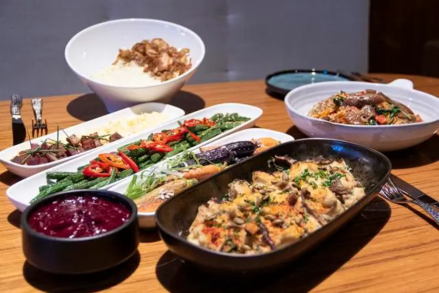 Thanksgiving Sides in white and black bowls on wooden tabletop